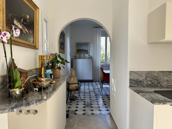 Interior of a renovated country house with an arch, plants and a black and white tiled floor.