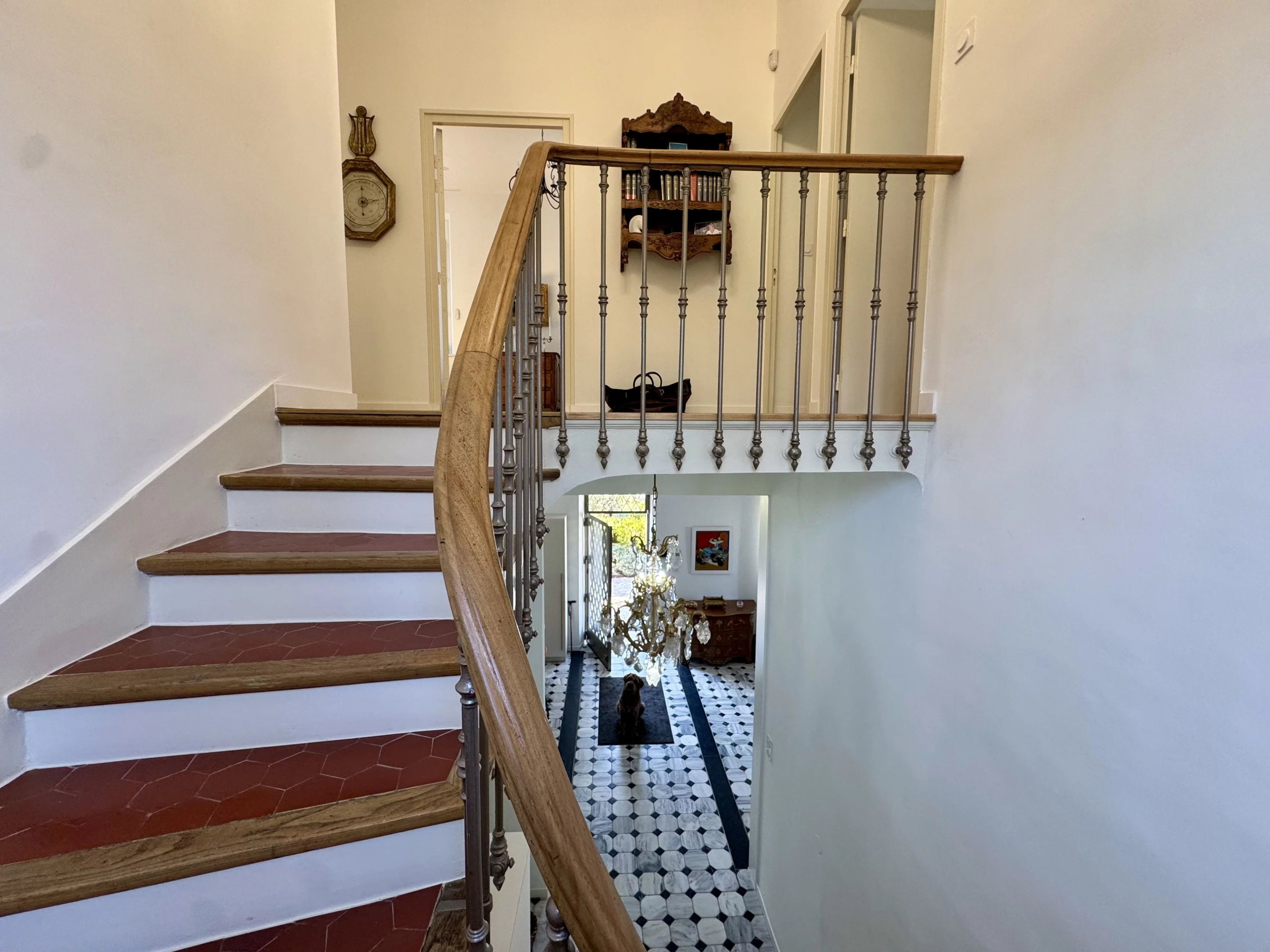 Wooden staircase leading to an entrance hall with black and white tiles in a bastide in Marseille.