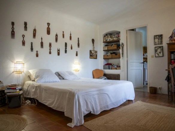 Chambre avec lit double, décorée de sculptures murales en bois et meubles en bois, dans une propriété à La Cadière-d'Azur.