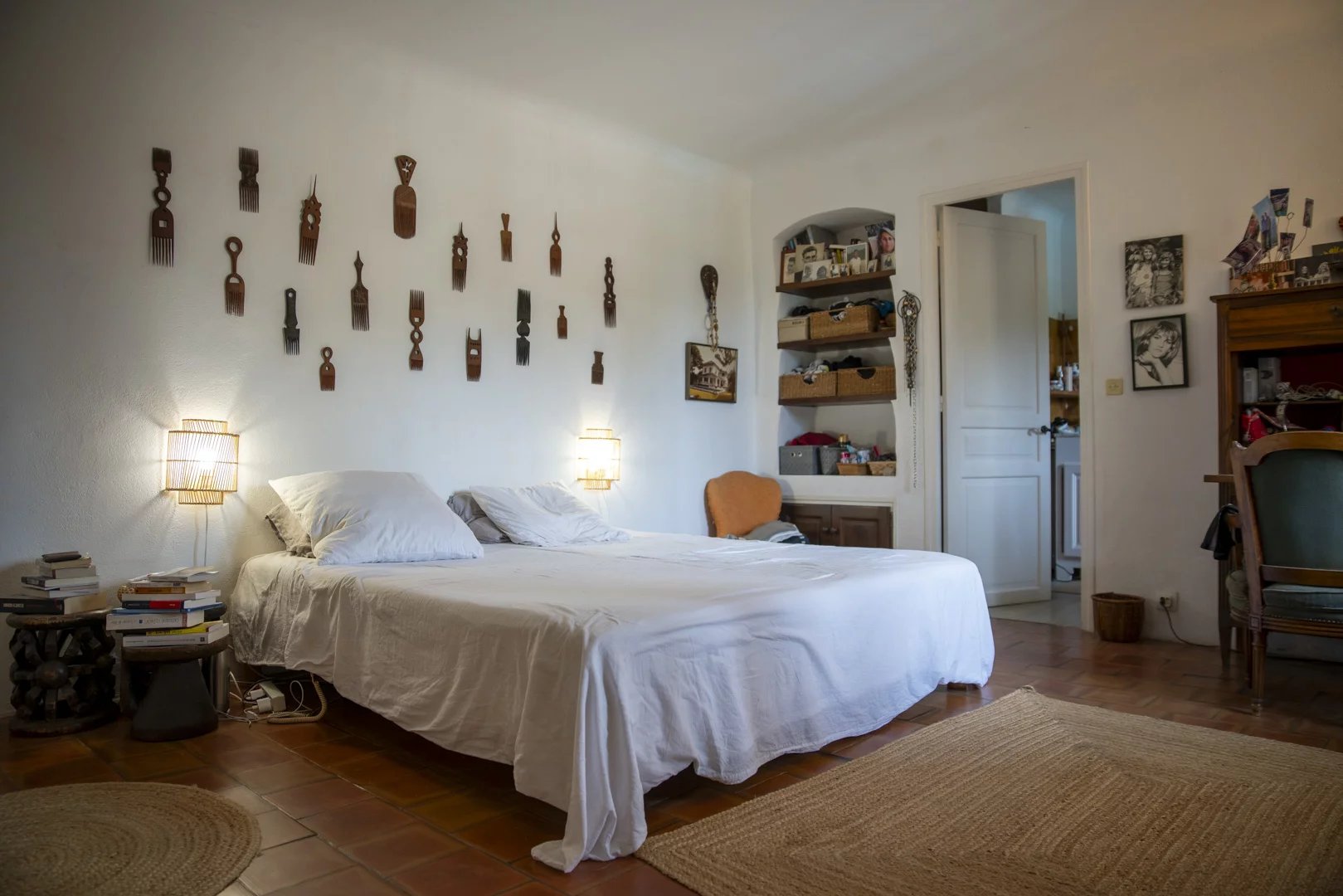 Chambre avec lit double, décorée de sculptures murales en bois et meubles en bois, dans une propriété à La Cadière-d'Azur.