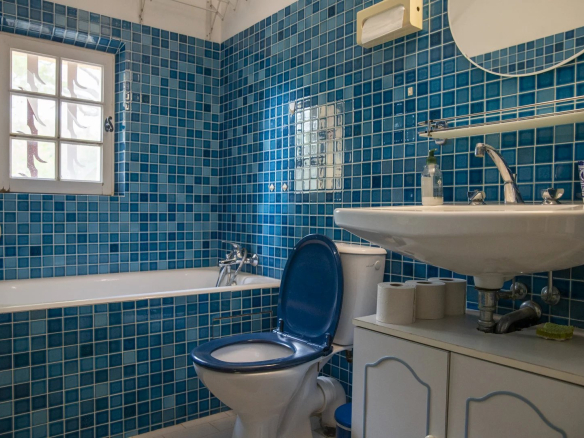 Salle de bain avec carrelage bleu, baignoire et lavabo dans une propriété à La Cadière-d'Azur.