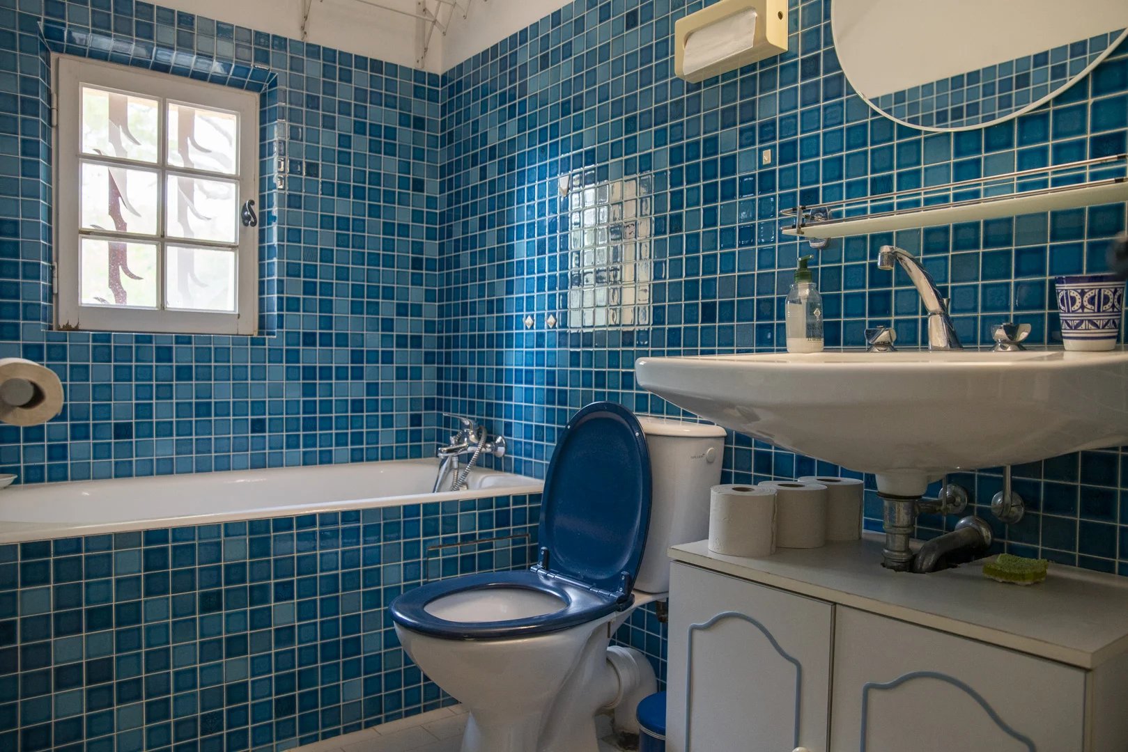 Salle de bain avec carrelage bleu, baignoire et lavabo dans une propriété à La Cadière-d'Azur.