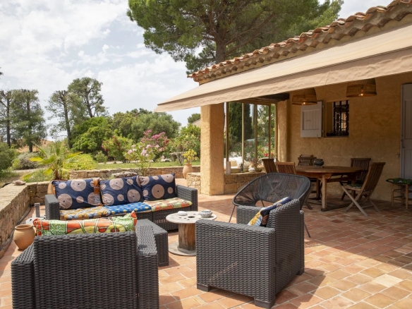 Terrasse d'une propriété avec mobilier en osier et vue sur un jardin verdoyant à La Cadière-d'Azur.