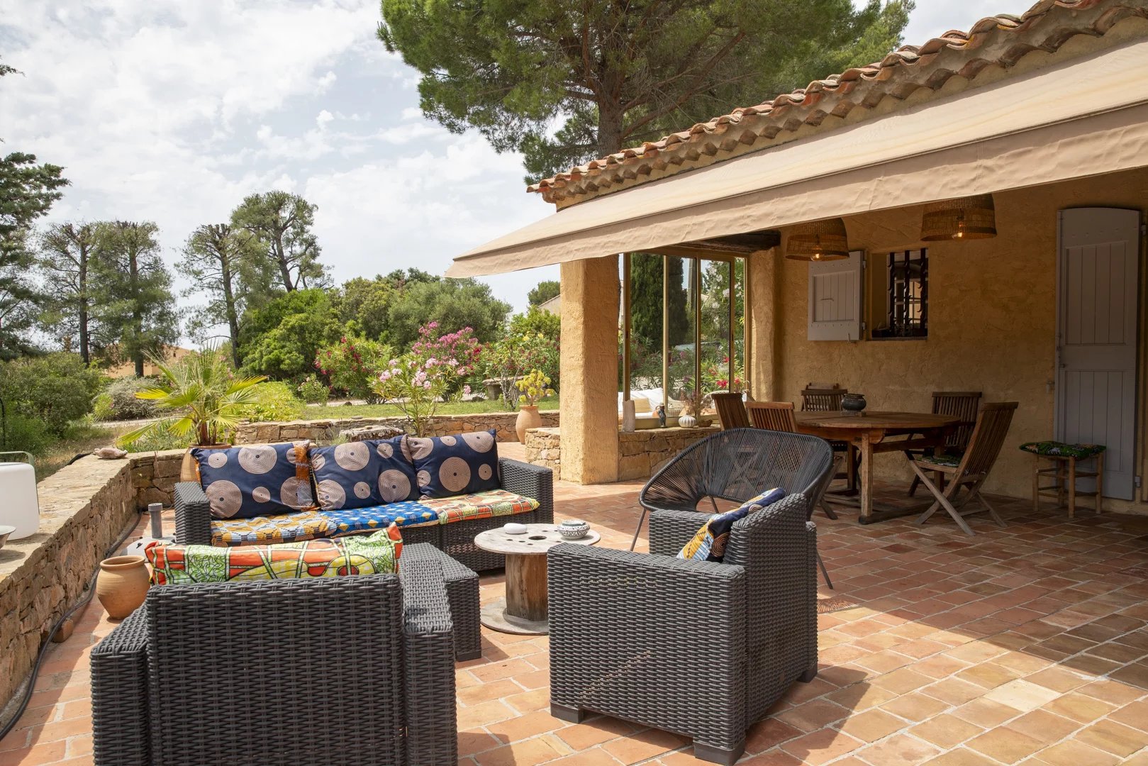 Terrasse d'une propriété avec mobilier en osier et vue sur un jardin verdoyant à La Cadière-d'Azur.
