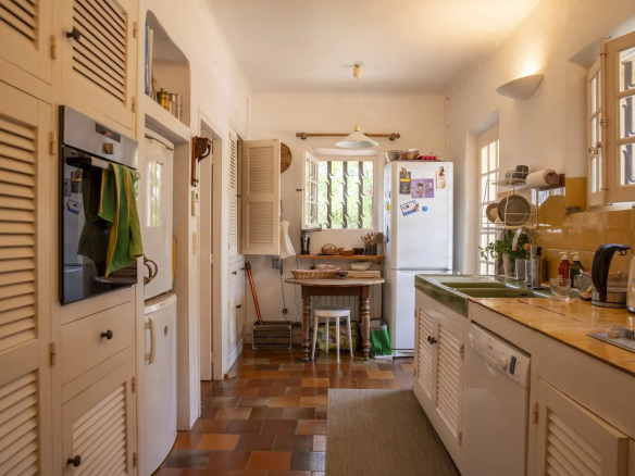 Cuisine lumineuse avec meubles en bois et appareils électroménagers, ambiance chaleureuse.