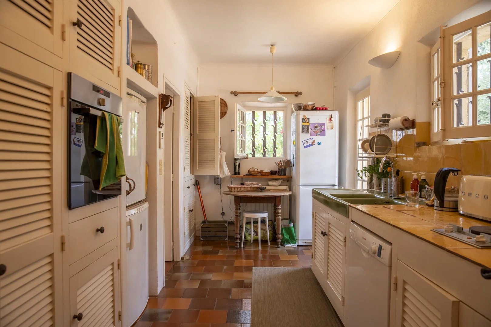 Cuisine lumineuse avec meubles en bois et appareils électroménagers, ambiance chaleureuse.
