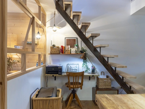 Intérieur d'un immeuble avec un bureau sous un escalier en bois.