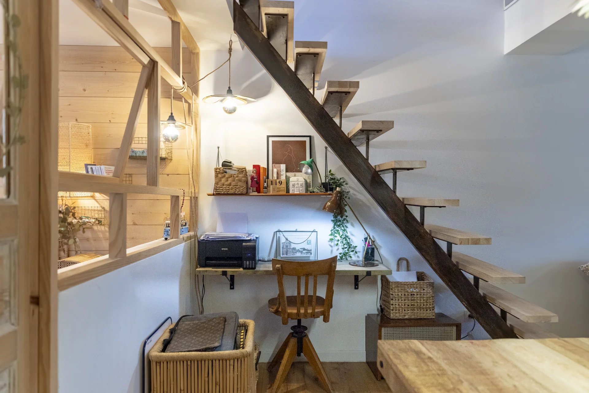 Intérieur d'un immeuble avec un bureau sous un escalier en bois.