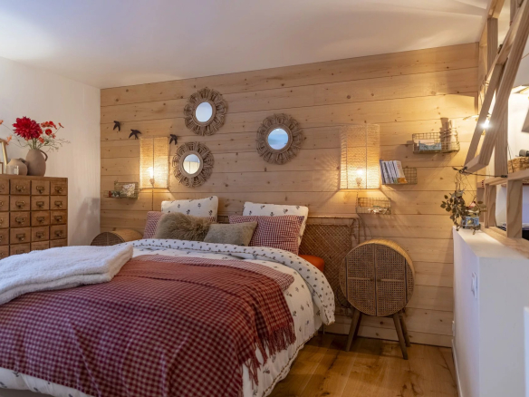 Chambre cosy avec murs en bois, lit confortable et décoration chaleureuse.