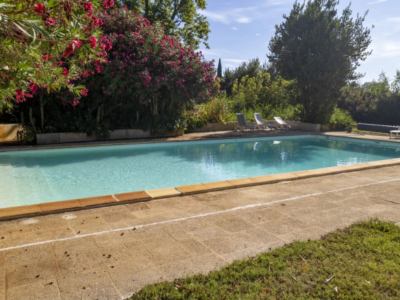 Swimming pool surrounded by greenery in an estate in Fourques, with sun loungers nearby.