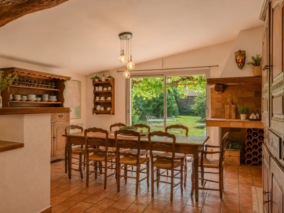 Interior of a dining room with a large wooden table and a view of a garden.