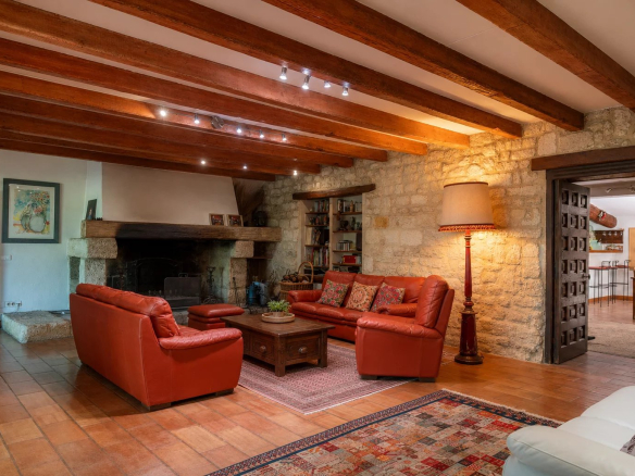 Interior of a living room with a red leather sofa and a stone fireplace, in a property in Fourques.