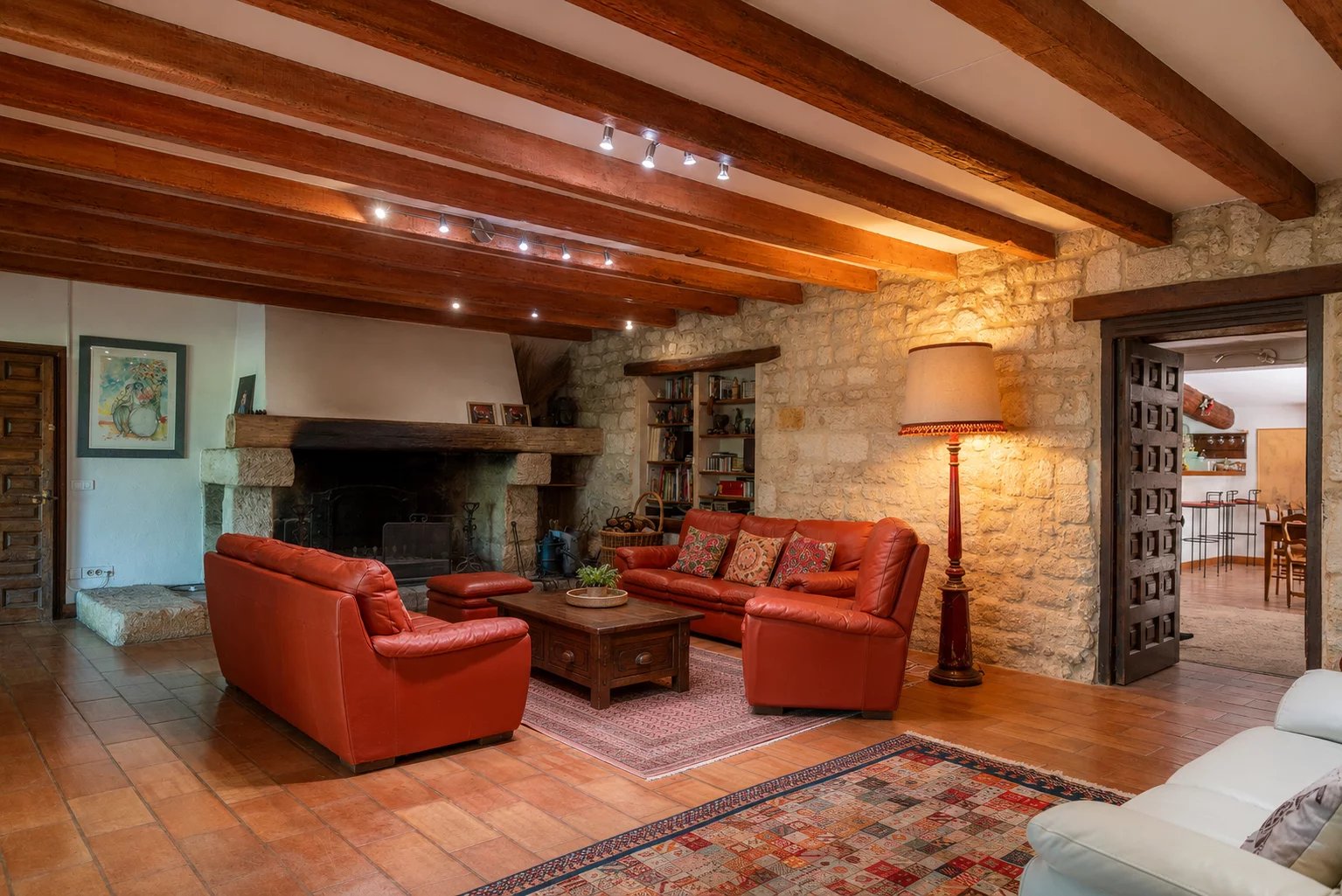 Living room of a property in Fourques Interior of a living room with a red leather sofa and a stone fireplace, in a property in Fourques.