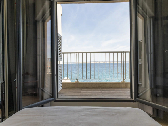 Vue depuis une chambre avec fenêtres ouvertes sur la mer Méditerranée à Marseille.
