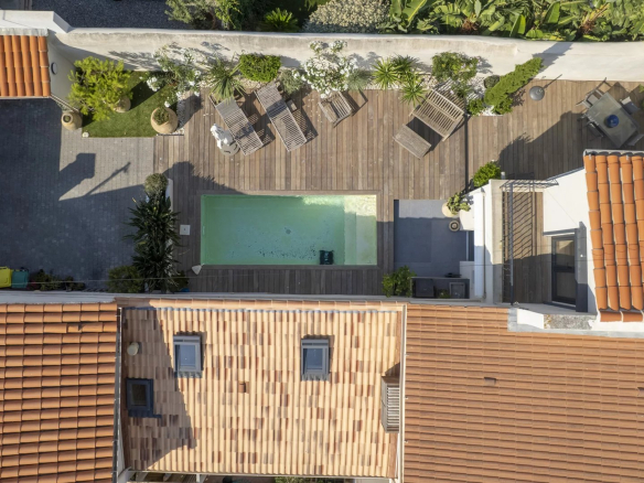 Vue aérienne d'une villa avec piscine et terrasses, entourée de végétation.