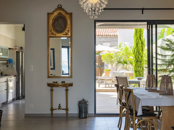 Intérieur d'une villa à Marseille avec vue sur la mer, table à manger et accès à une terrasse.