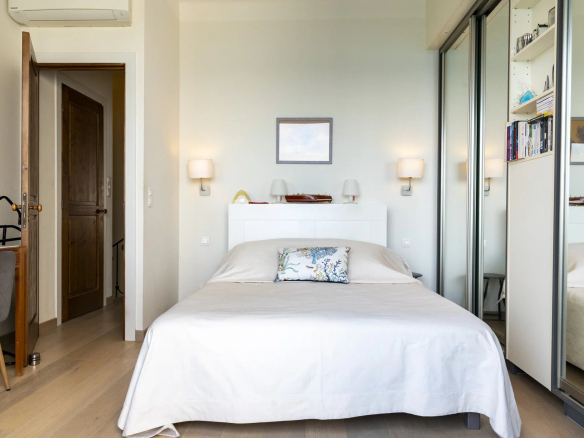 Chambre d'une villa moderne avec lit double et rangement, vue sur la mer.
