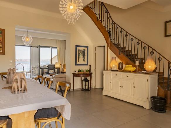 Intérieur d'une villa à Marseille avec vue sur la mer, salle à manger et escalier en bois.