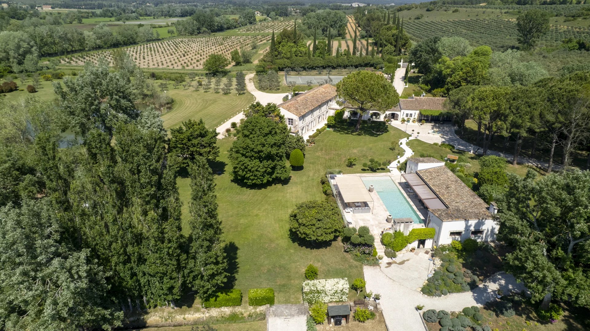 Vue aérienne d'une propriété dans le parc régional des Alpilles, avec jardins et piscine.