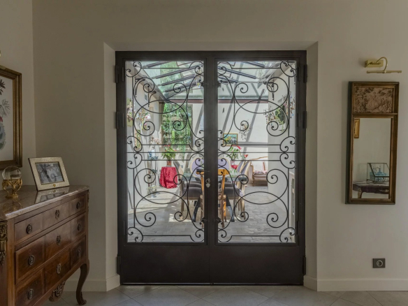 Entrée avec portes en fer forgé menant à un espace intérieur lumineux et décoré.