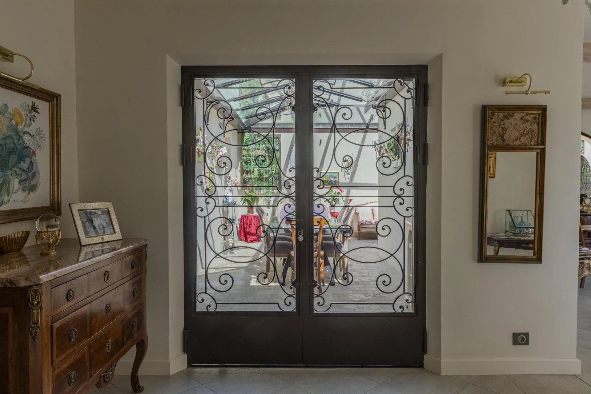 Entrée avec portes en fer forgé menant à un espace intérieur lumineux et décoré.