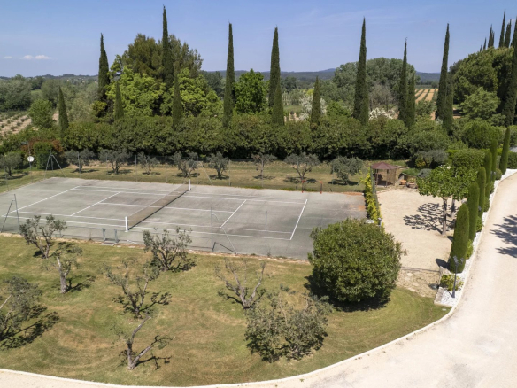 Vue aérienne d'un terrain de tennis entouré d'arbres et d'un parc paysager à Raphèle-lès-Arles.