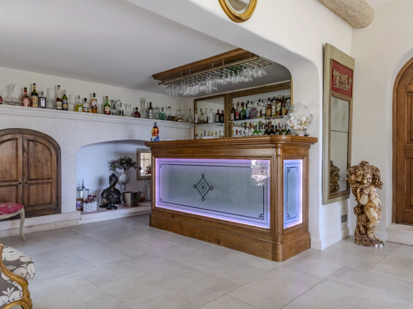 Intérieur d'une propriété avec un bar en bois et des bouteilles d'alcool sur une étagère.