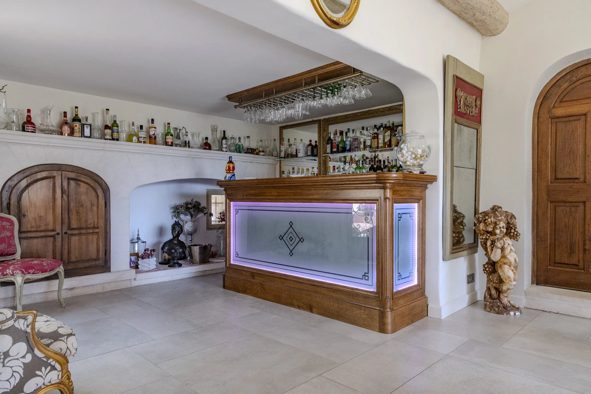 Intérieur d'une propriété avec un bar en bois et des bouteilles d'alcool sur une étagère.