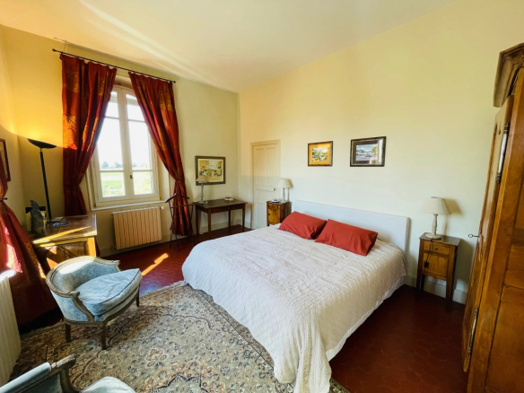 Room in a Provençal country house with double bed, armchair and classic decor.