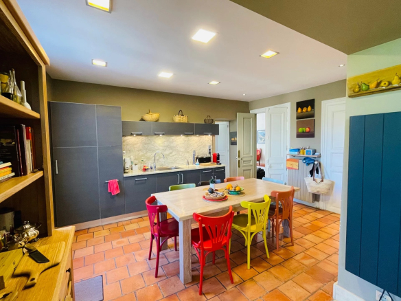 Modern kitchen with dining table and colorful chairs in a Provençal country house.