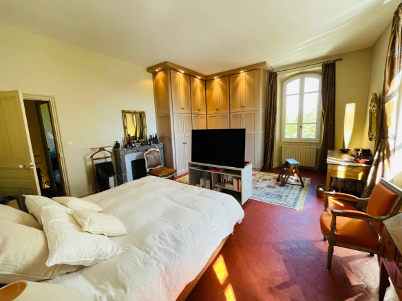 Spacious room with bed, television and elegant furniture in a Provençal country house.