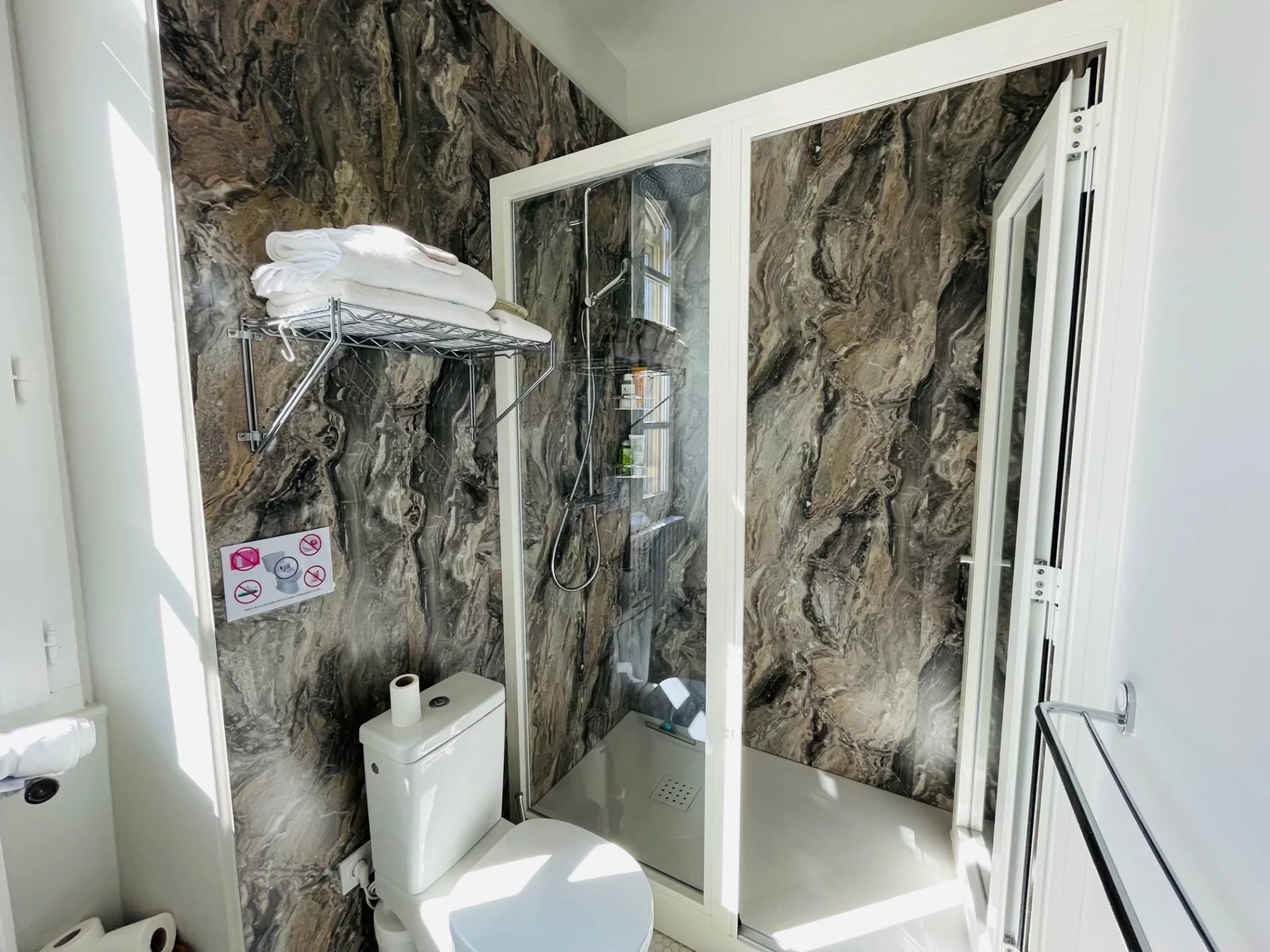 Modern bathroom Modern bathroom with shower and toilet, marble walls, natural lighting.
