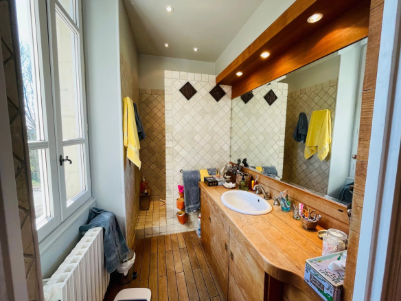 Bathroom with wooden sink and beige tiles, bright windows