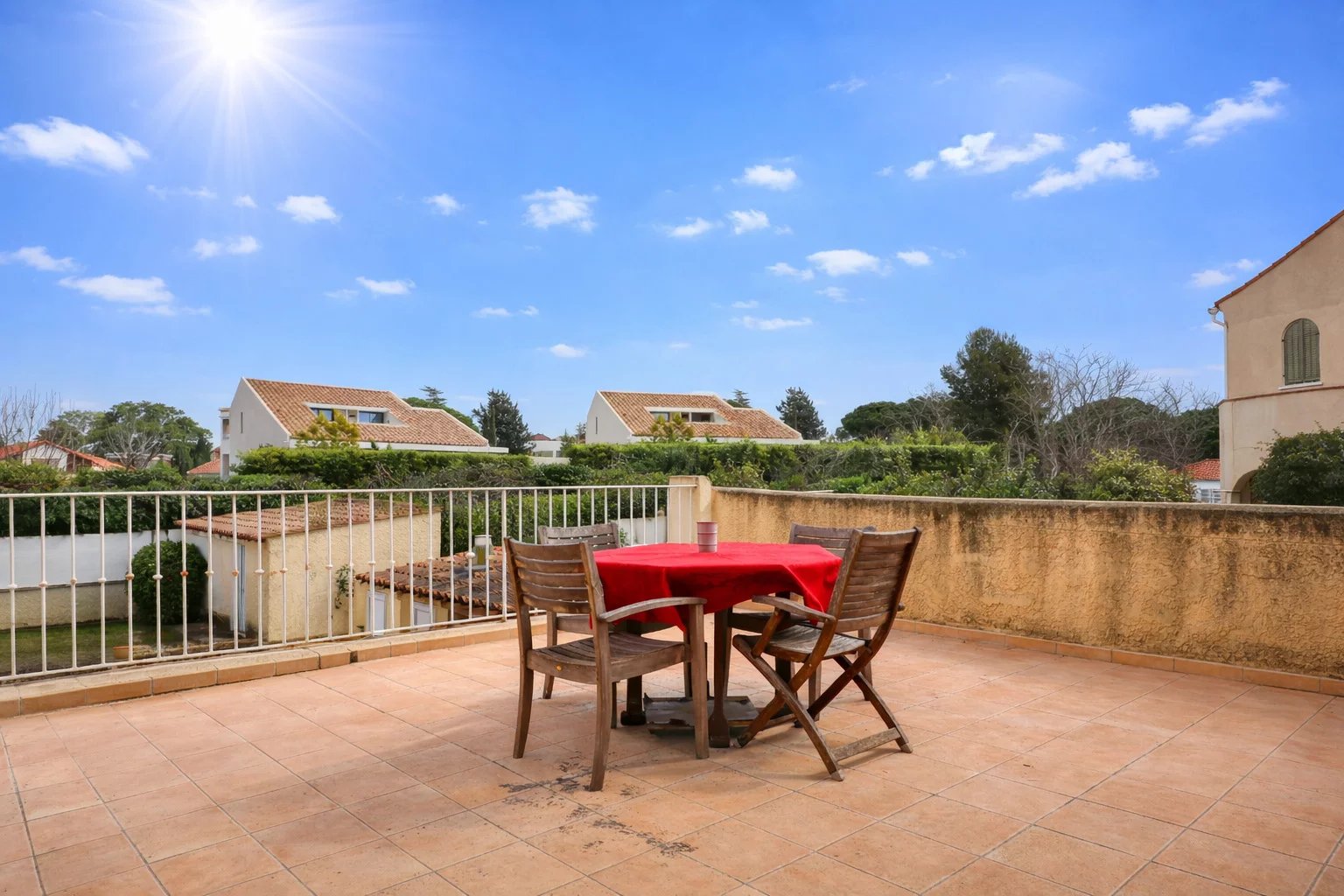 Terrasse d'une villa à Saint-Cyr-sur-Mer avec table et chaises, ciel bleu et maisons en arrière-plan.