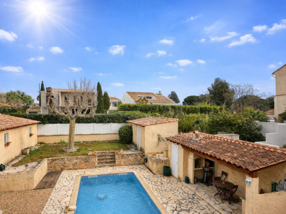 Vue d'une villa avec piscine et jardins à Saint-Cyr-sur-Mer, ensoleillée, avec des bâtiments en pierre.