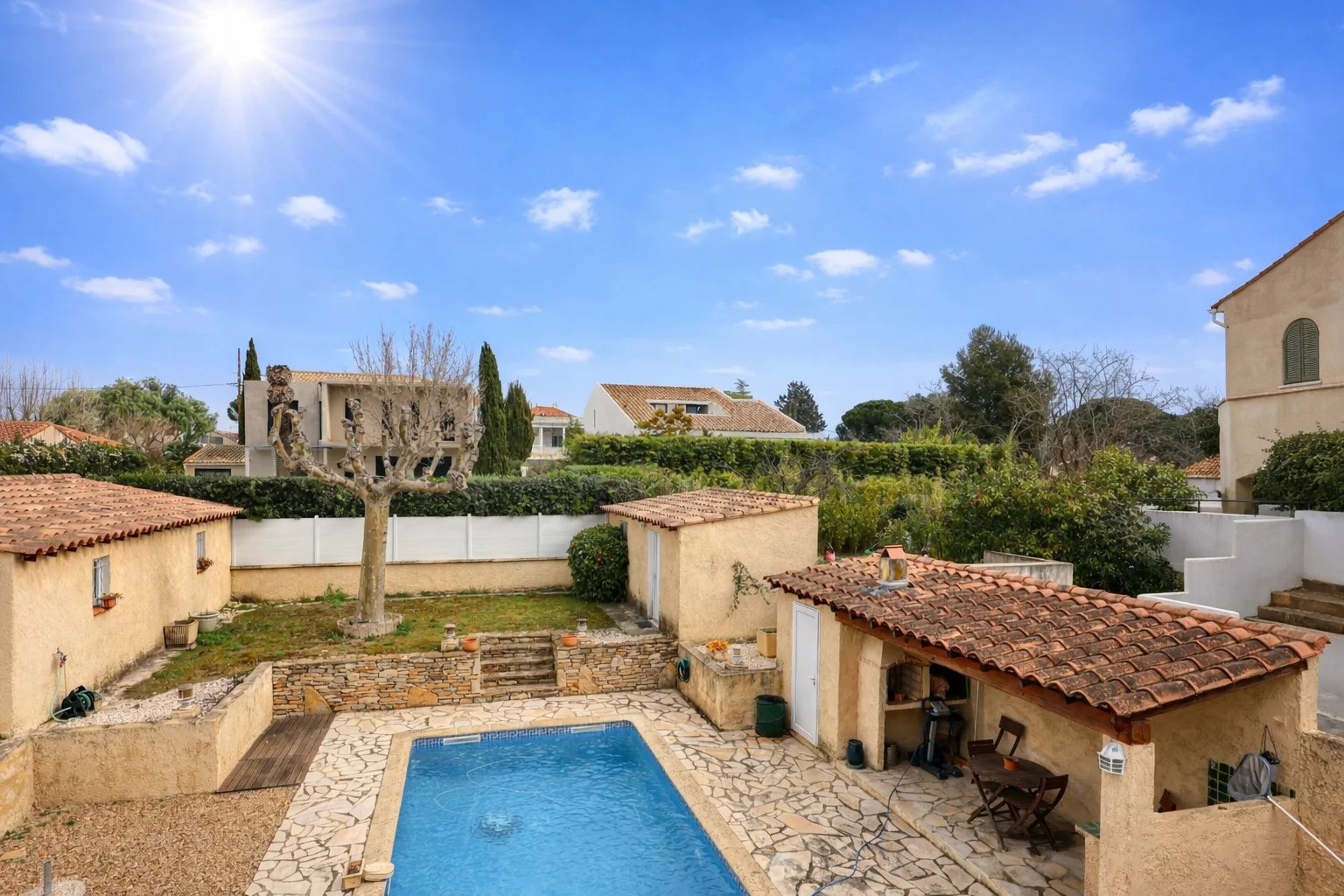 Vue d'une villa avec piscine et jardins à Saint-Cyr-sur-Mer, ensoleillée, avec des bâtiments en pierre.