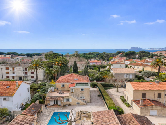 Vue panoramique sur des villas et la mer à Saint-Cyr-sur-Mer, avec piscine au premier plan.
