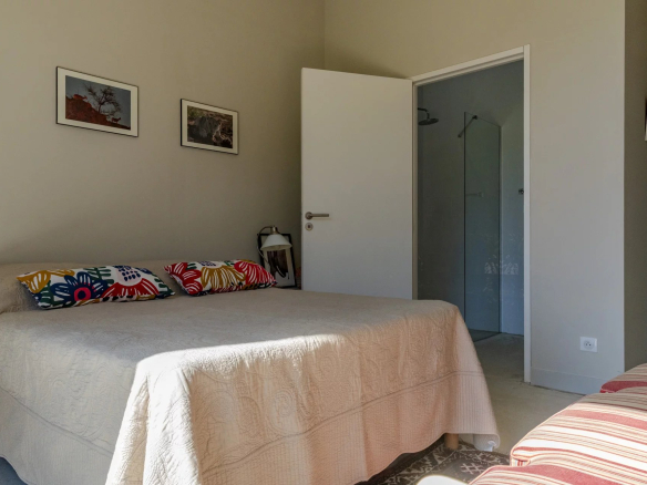 Chambre d'une villa contemporaine avec lit double et salle de bain attenante.