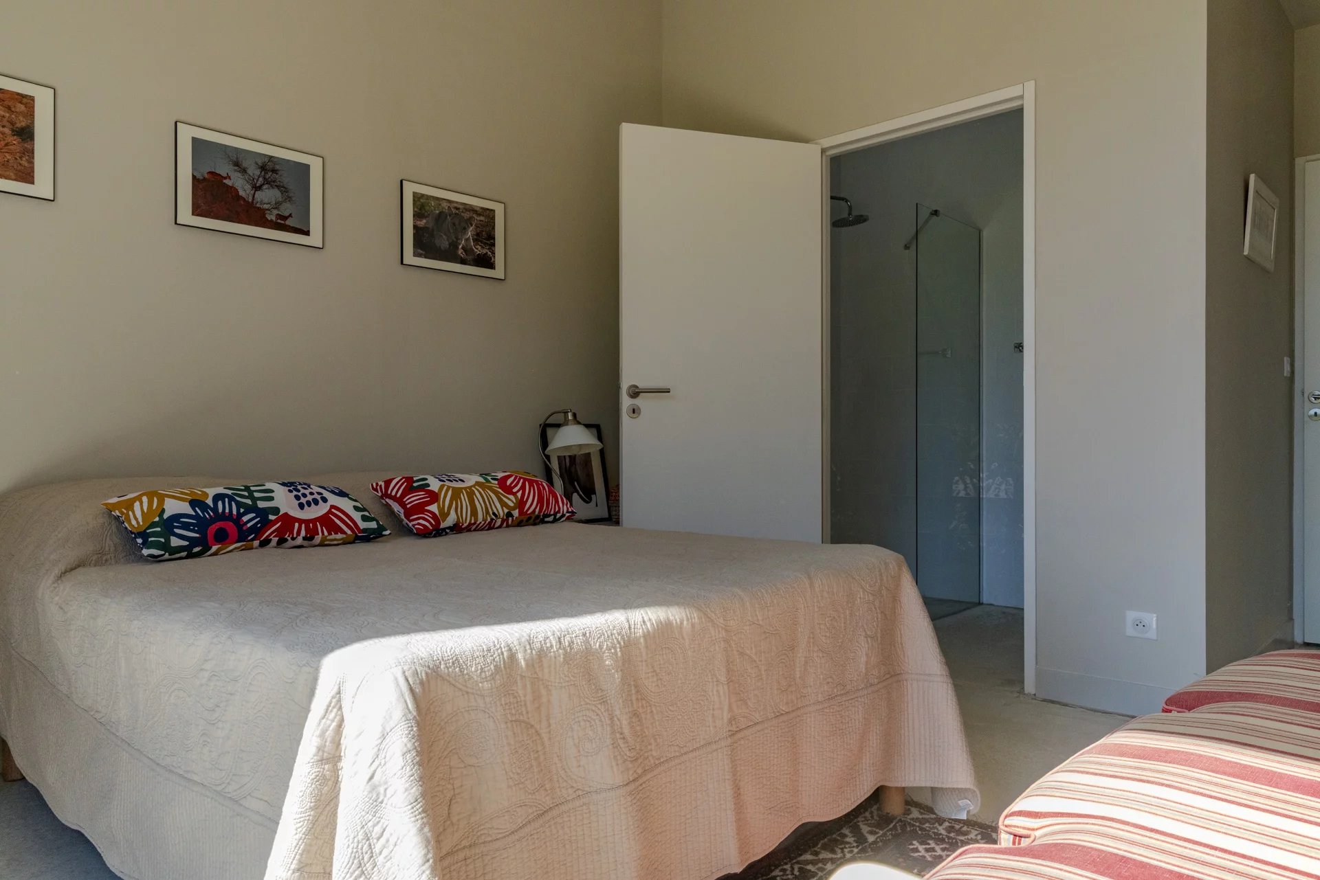 Chambre d'une villa contemporaine avec lit double et salle de bain attenante.