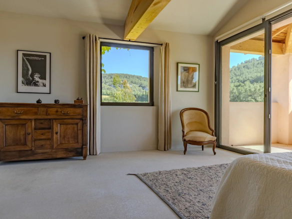 Intérieur d'une villa contemporaine avec vue sur les collines, mobilier en bois et fenêtre lumineuse.