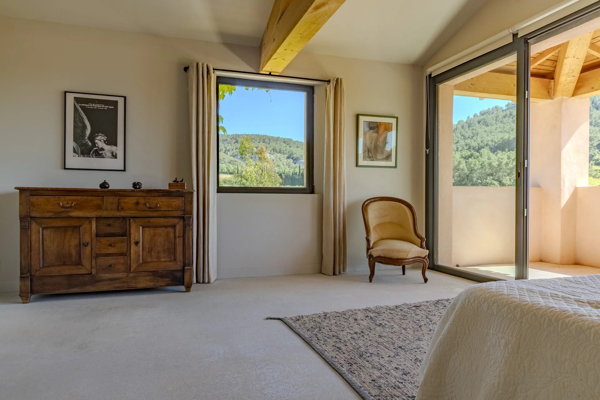 Intérieur d'une villa contemporaine avec vue sur les collines, mobilier en bois et fenêtre lumineuse.
