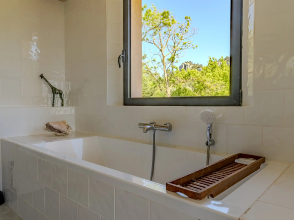 Salle de bain moderne avec baignoire et fenêtre donnant sur la nature.