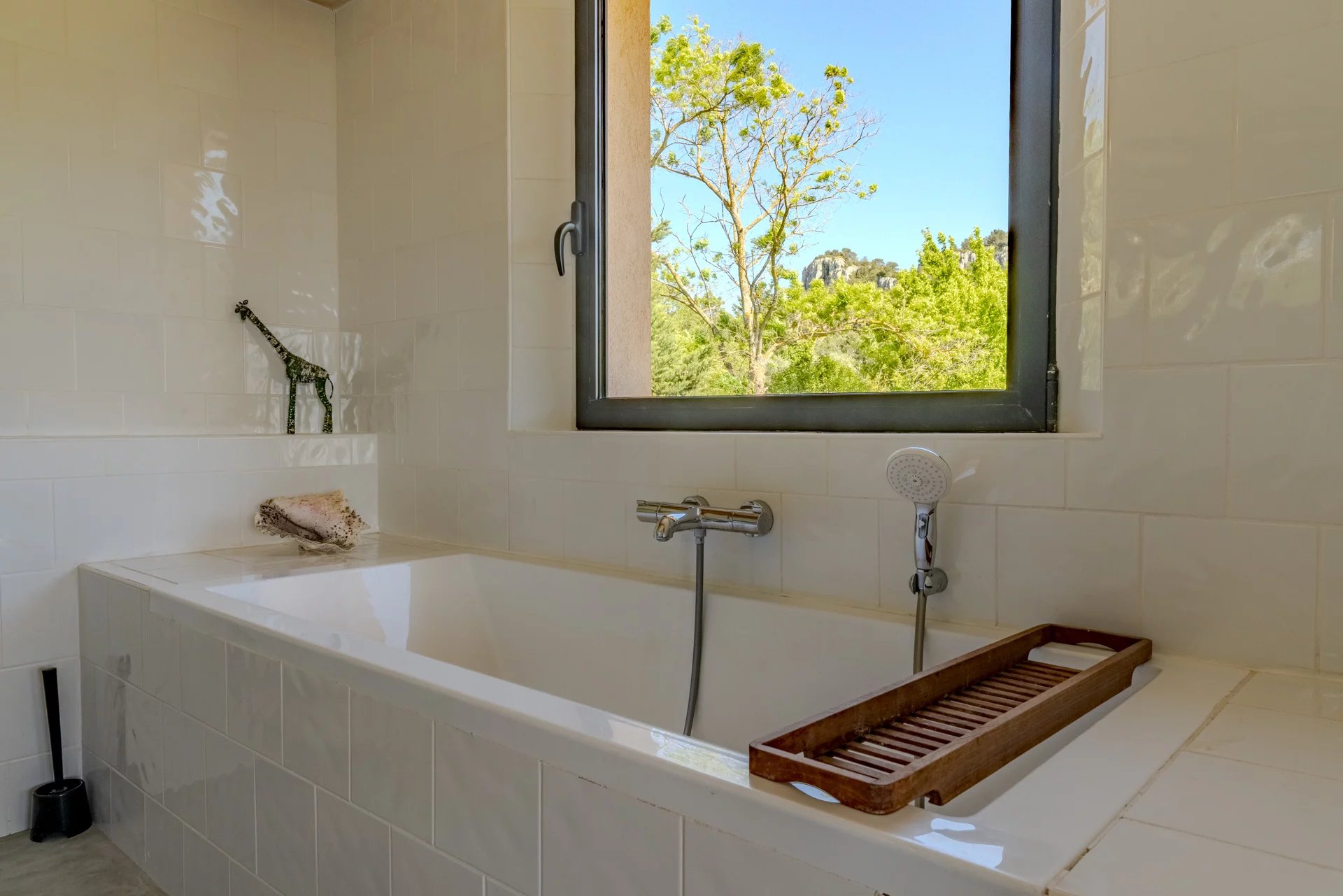 Salle de bain moderne avec baignoire et fenêtre donnant sur la nature.