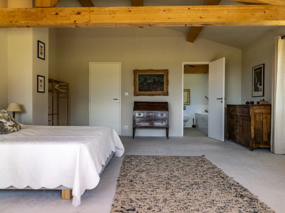 Chambre spacieuse d'une villa contemporaine à Roquefort-la-Bédoule, avec lit, meubles en bois et décoration sobre.