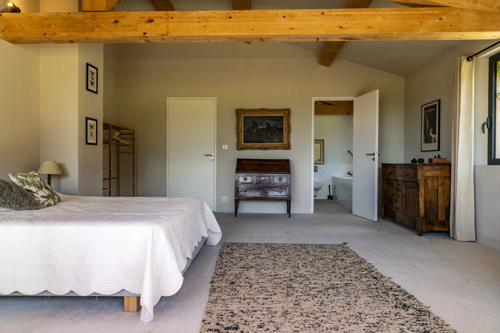 Chambre spacieuse d'une villa contemporaine à Roquefort-la-Bédoule, avec lit, meubles en bois et décoration sobre.