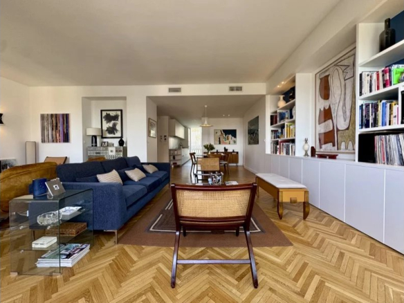 Salon lumineux d'un appartement rénové avec mobilier contemporain, parquet en bois, et œuvres d'art.
