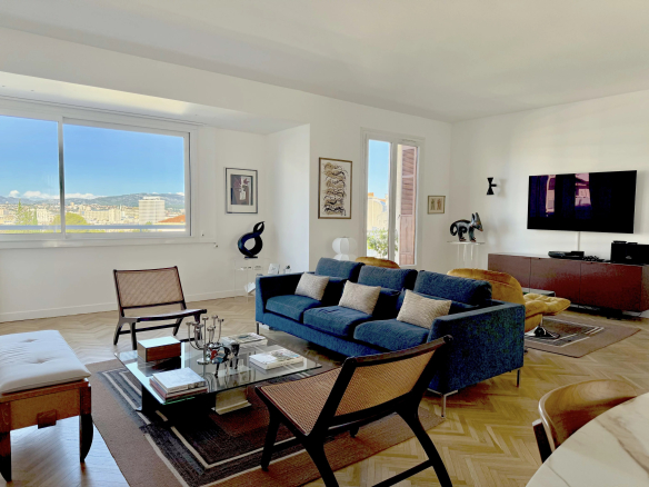 Salon lumineux d'un appartement rénové avec canapé bleu et vue sur la ville.