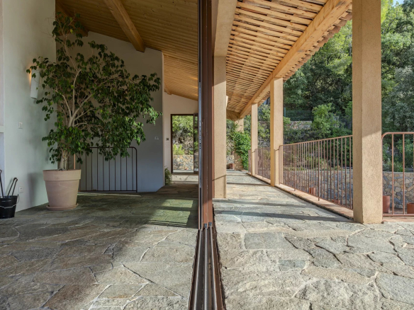 Intérieur d'une villa contemporaine avec un sol en pierre et des éléments de bois, entourée de nature.
