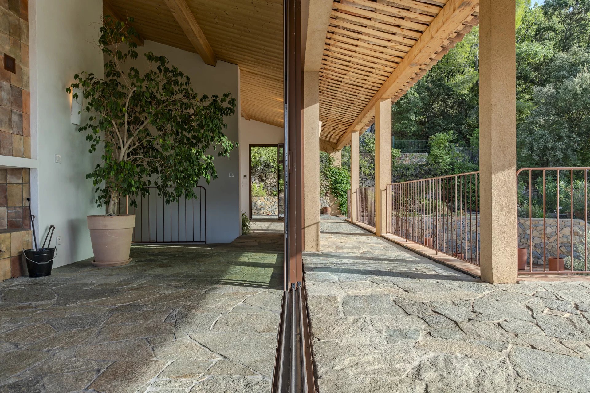 Intérieur d'une villa contemporaine avec un sol en pierre et des éléments de bois, entourée de nature.