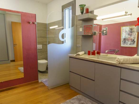Modern bathroom with sink, mirror and separate toilet.